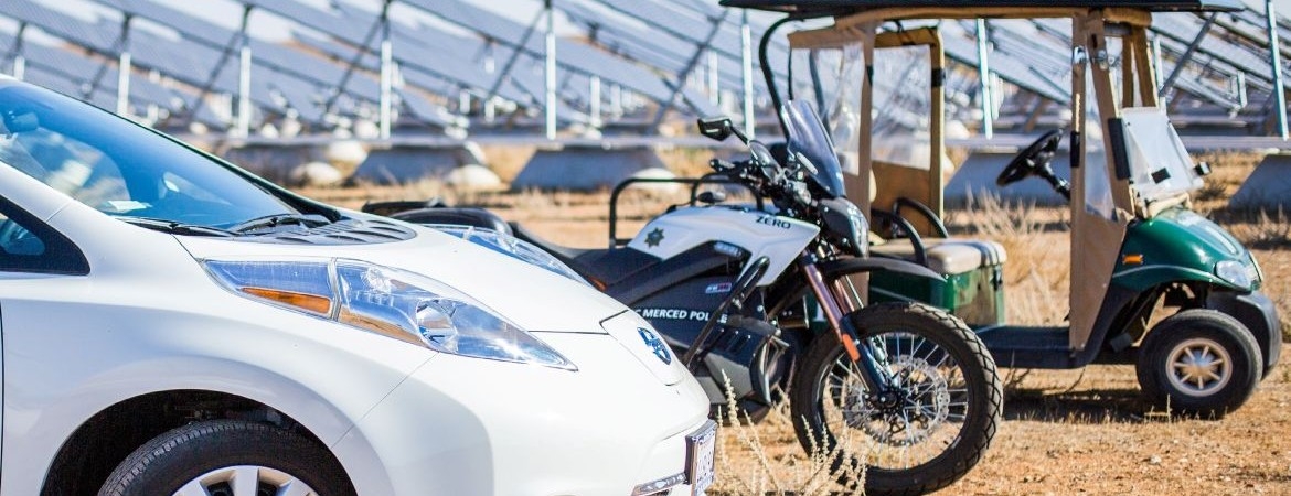 Eco-friendly fleet vehicles parked in front of solar panels